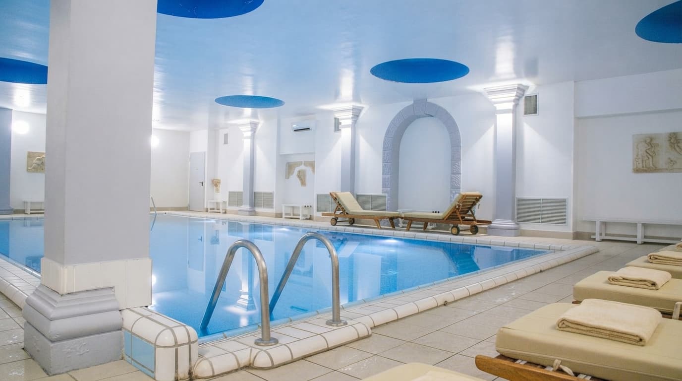 Indoor swimming pool with classic white columns and relaxation loungers